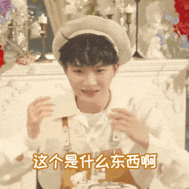 a young man wearing a hat and suspenders is holding a piece of paper with chinese characters on it