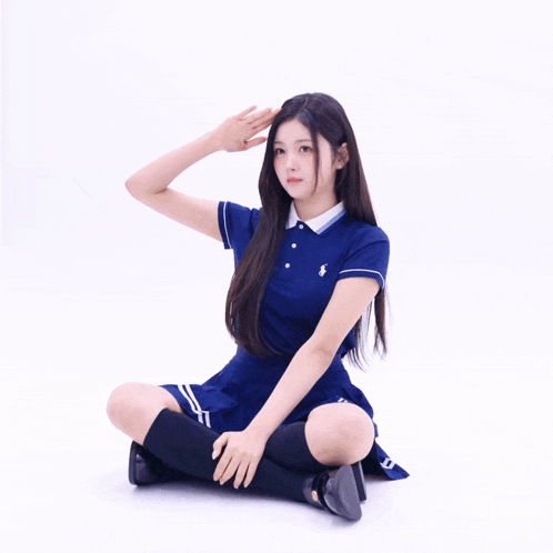 a girl in a blue polo dress is sitting on the floor