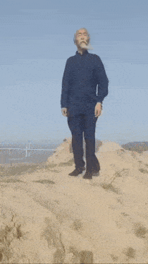 a man with a beard is standing on top of a hill