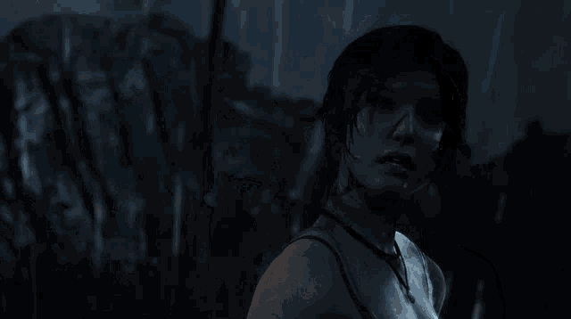 a woman with a necklace around her neck looks at something in the dark