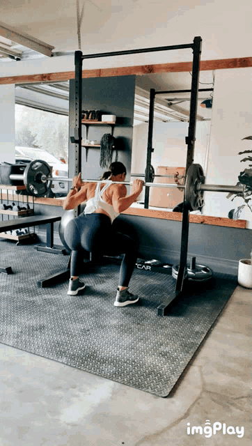 a woman squatting with a barbell in a gym with imgplay written on the bottom