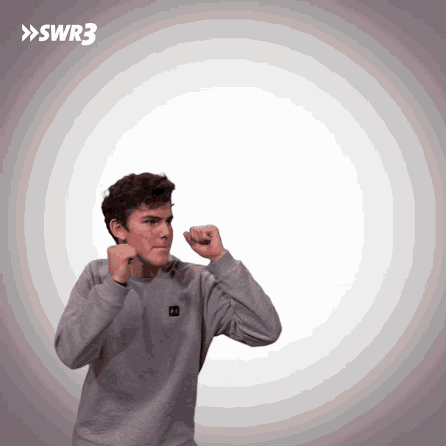 a man in a grey under armour sweatshirt stands in front of a white background with the letters swr3 on it