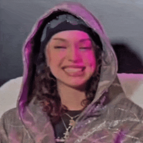 a close up of a woman wearing a hoodie and a headband .