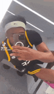 a man wearing a headband is taking a picture of himself in a mirror .