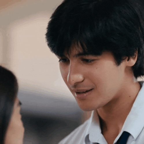 a young man in a white shirt and tie looks at a woman