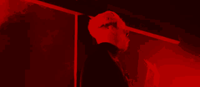 a man wearing sunglasses is standing in a red light
