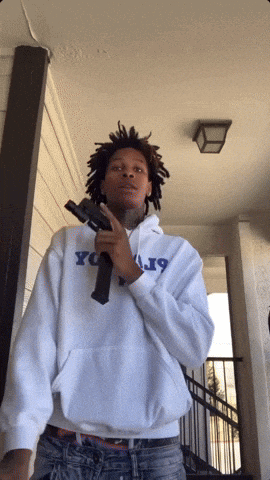 a man holding a gun wearing a hoodie that says j19