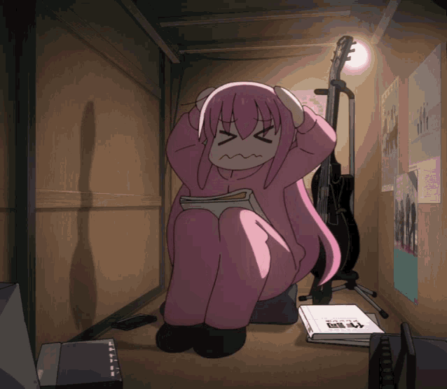 a girl with pink hair is sitting in a room with posters on the wall and a guitar on a stand