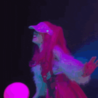 a woman with red hair and a pink hat is holding a pink ball in a dark room .