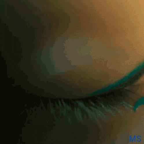 a close up of a woman 's eye with green mascara