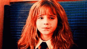 a young girl with red hair and a white shirt and tie is making a sad face .