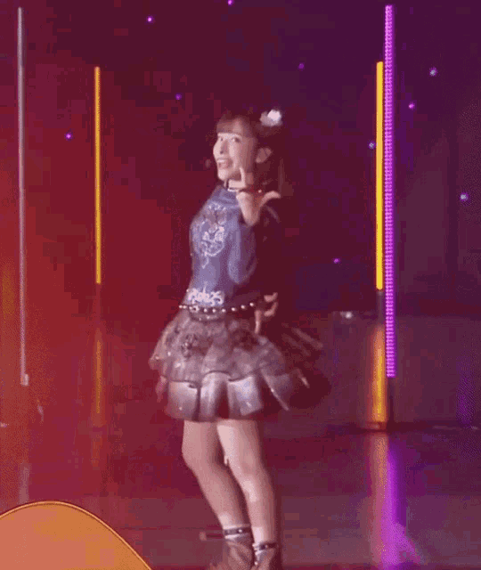 a woman in a blue top and a black skirt is smiling