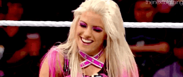 a blonde woman is smiling in a wrestling ring .