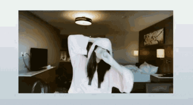a woman in a pink robe is stretching in a hotel room