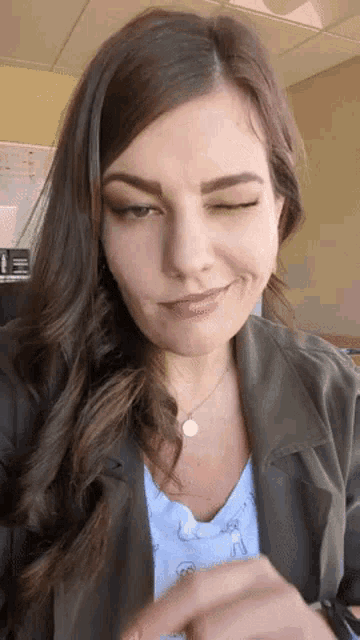 a woman is making a funny face while wearing a necklace and a jacket .