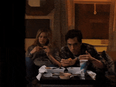 a man and a woman are sitting on a couch eating