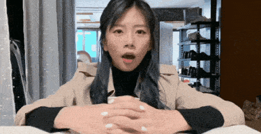 a woman sitting at a table with her hands folded and a surprised look on her face