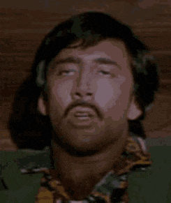 a man with a mustache is laying down with his eyes closed and his head is visible .