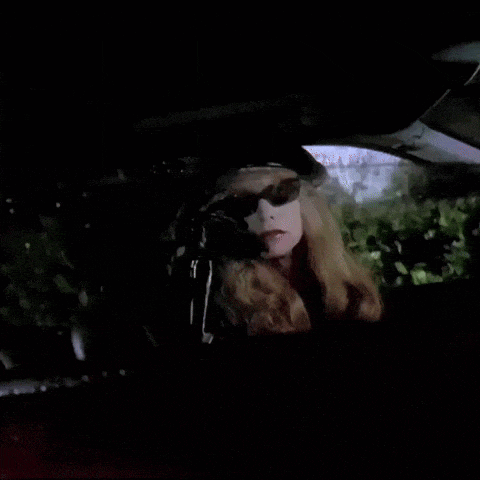 a woman wearing sunglasses and a hat is sitting in the back seat of a car