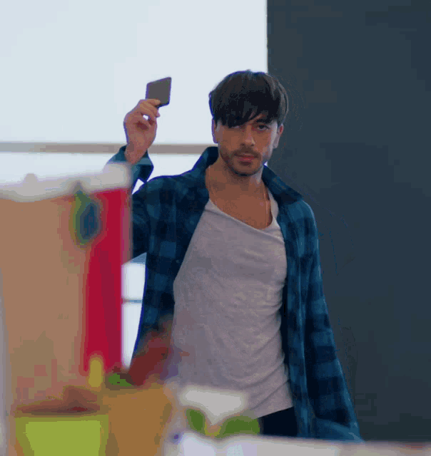 a man in a plaid shirt is holding a piece of paper in his hand