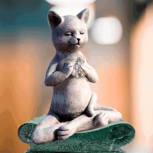 a statue of a cat sitting in a lotus position with its eyes closed and holding a mouse
