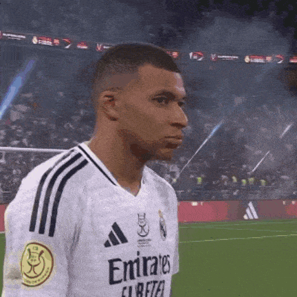 a soccer player wearing an emirates jersey is standing on the field