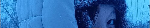 a close up of a woman 's face behind a blue blanket .