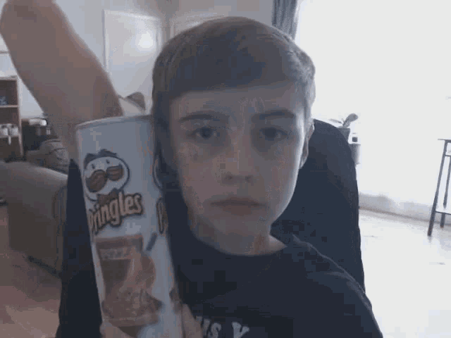 a young boy holds a can of pringles chips