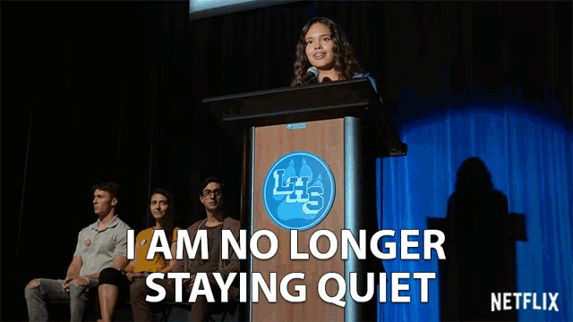 a woman stands at a podium with the words " i am no longer staying quiet " above her
