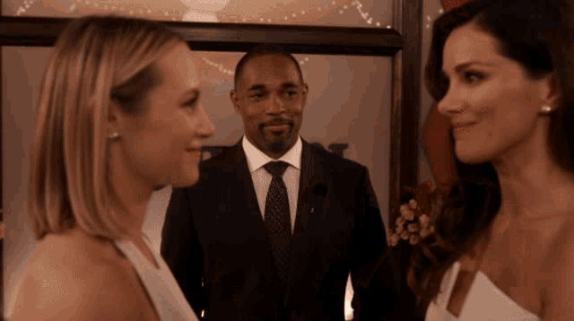 a man in a suit and tie is standing next to two women