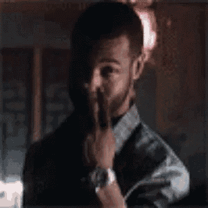 a man with a beard and a watch is covering his mouth with his hand .