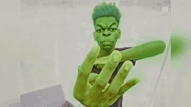 a young man with green hair is making a hulk hand gesture .
