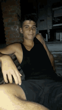 a young man in a black tank top is laying on his back
