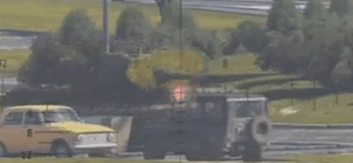 a yellow car with the number 8 on the side is driving down a road next to a truck .