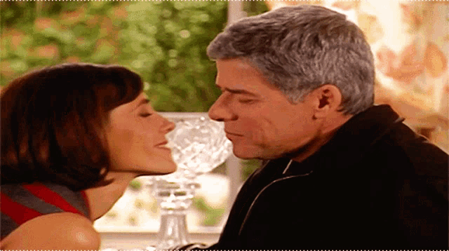 a man and a woman are kissing in front of a vase