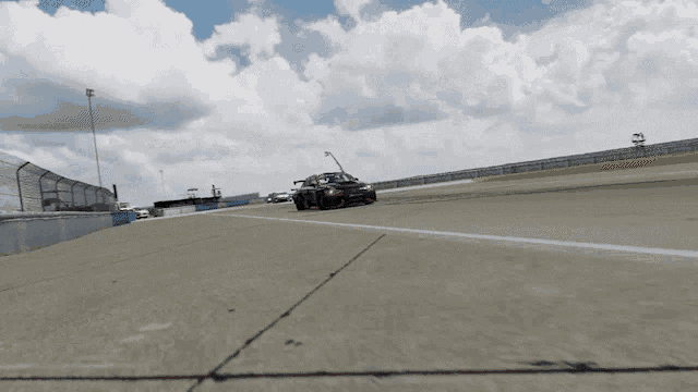 a race car is driving down a track with a fence around it