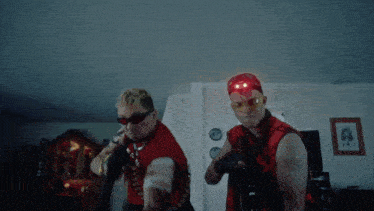 a man in a red vest is holding a gun and wearing sunglasses
