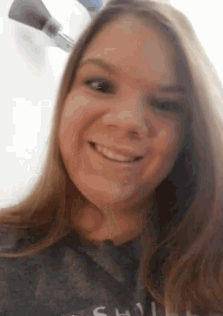 a woman is smiling and looking at the camera while wearing a shirt that says ' silly ' on it .