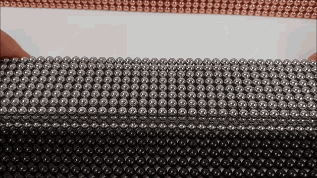a person is holding a bunch of metal beads in their hands .