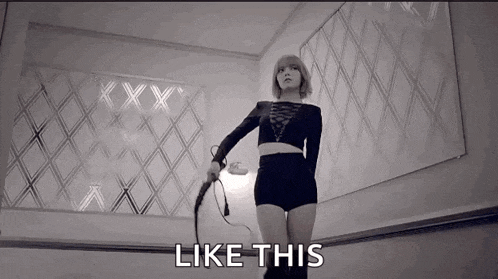 a woman is holding a whip in a black and white photo and the words `` like this '' are next to her .