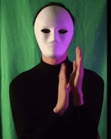 a man wearing a white mask is clapping his hands in front of a green screen