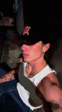 a man wearing a hat with the letter m on it is taking a selfie