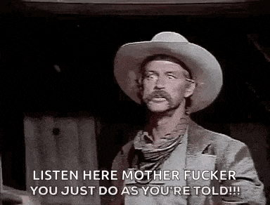 a man in a cowboy hat is standing in a dark room .