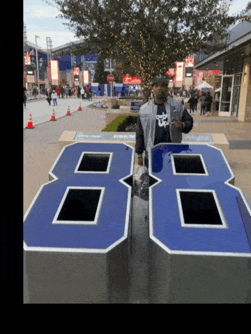 a man stands in front of a large blue number 86 sign