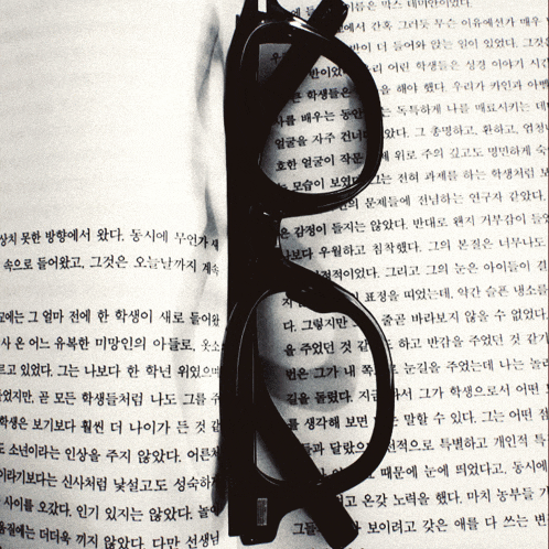 a pair of glasses with a magnifying glass on top of a page of korean text