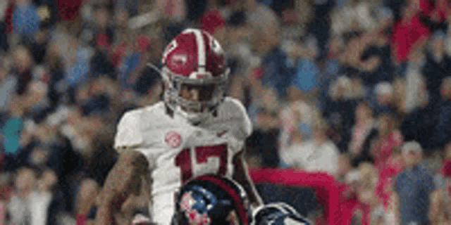 a football player wearing a white jersey with the number 15 on it is running on the field .