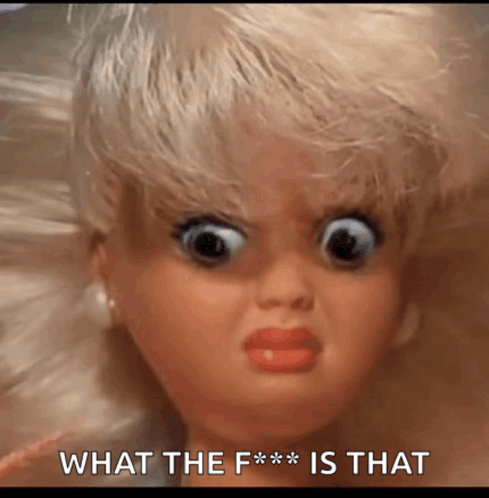 a close up of a doll 's face with the words what the f *** is that behind it