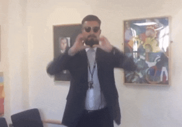 a man in a suit and sunglasses is taking a picture