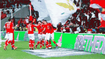 a group of soccer players are celebrating a goal in front of a banner that says netbet