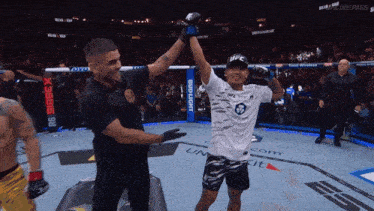 a referee holds up a fighter 's arm in a ufc ring